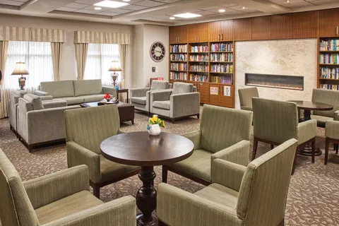 Library lounge with bookshelves, armchairs and a fireplace