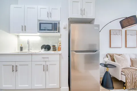 Suite kitchenette with white cabinets and appliances