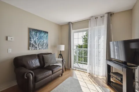 Sitting area with a dark sofa, television and balcony door