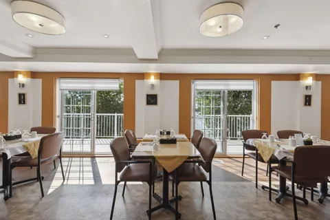 Set dining tables and upholstered chairs beside balcony doors