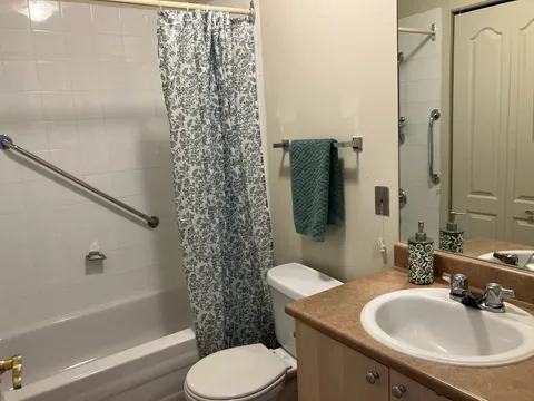 Bathroom with a bathtub, sink, toilet and grab bars
